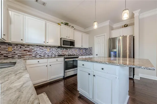a kitchen with granite countertop a sink stainless steel appliances and white cabinets