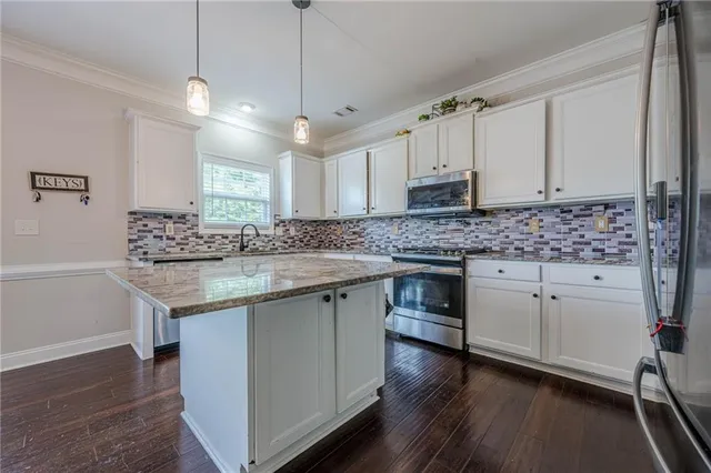 a kitchen with stainless steel appliances granite countertop a sink stove and white cabinets with wooden floor