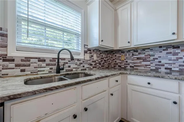 a kitchen with granite countertop white cabinets and a sink