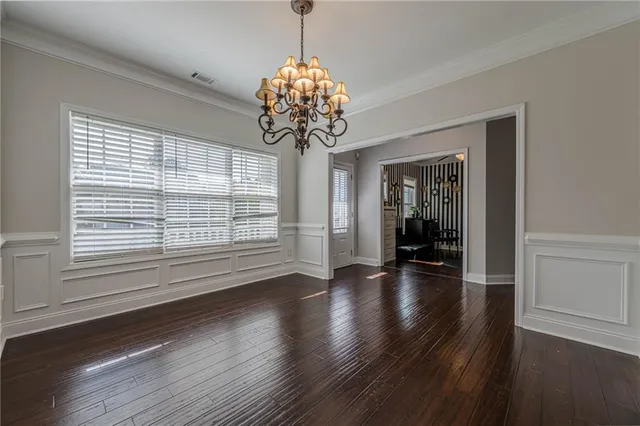 a dining room with wooden floor chandelier and windows
