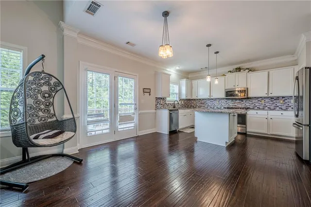 a open kitchen with stainless steel appliances granite countertop a stove a sink dishwasher and a dining table with wooden floor