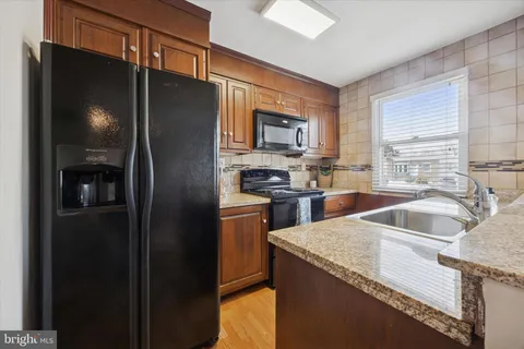 a kitchen with granite countertop stainless steel appliances a refrigerator a sink a stove and cabinets
