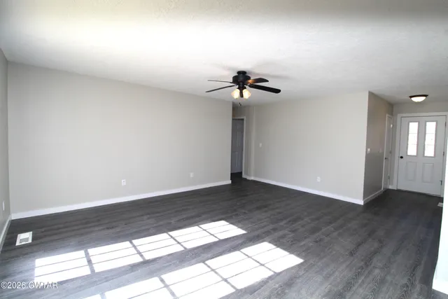 a view of an empty room with a window and wooden floor