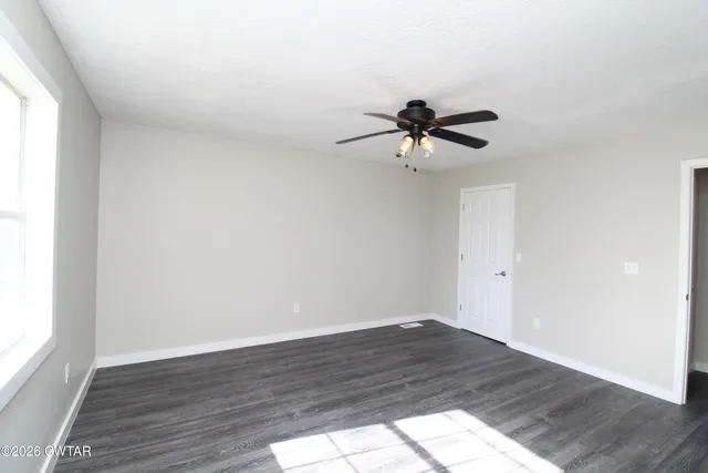 an empty room with wooden floor and ceiling fan