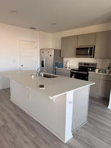 a kitchen with stainless steel appliances a sink a stove a microwave and wooden floor