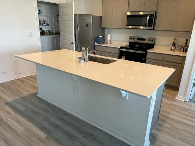 a kitchen with stainless steel appliances a sink a stove a microwave and wooden floor