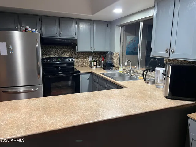 a kitchen with granite countertop a refrigerator and a stove top oven