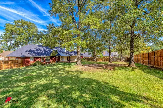 a view of a house with a big yard and large tree