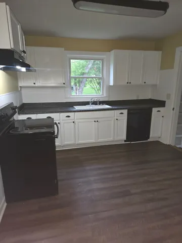a kitchen with granite countertop a sink window and cabinets