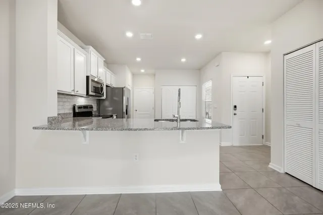 a large kitchen with stainless steel appliances a refrigerator a stove a sink a microwave and a refrigerator