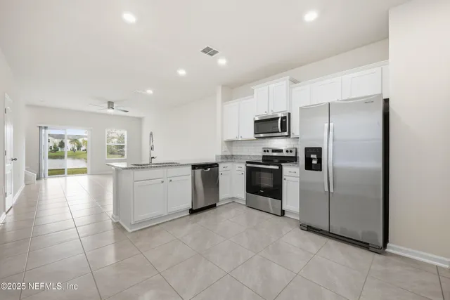 a large kitchen with a refrigerator a stove top oven a sink and dishwasher
