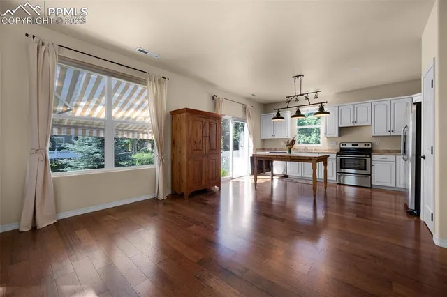 a view of a kitchen with refrigerator and wooden floor