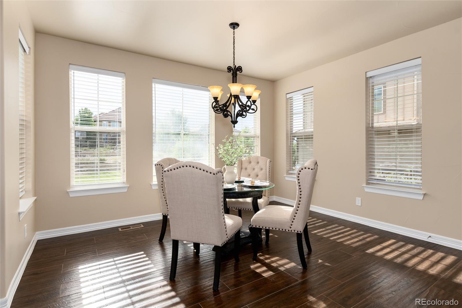 10703 Braesheather Court Highlands Ranch, CO 80126 - Photo 26 of 48 a dining room with wooden floor a chandelier a glass table and chairs