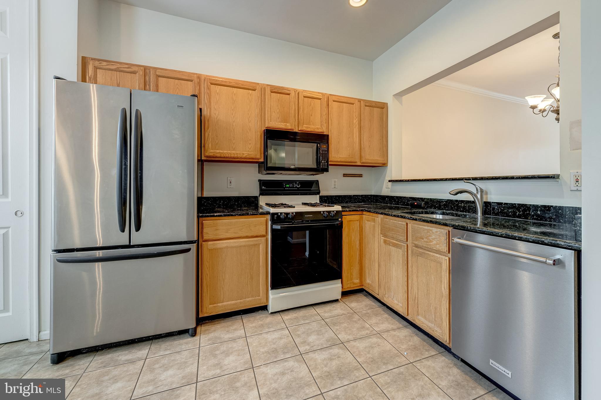 11444 Heritage Commons Way Reston, VA 20194 - Photo 10 of 35 a kitchen with granite countertop a refrigerator and a stove top oven
