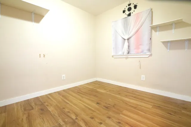 an empty room with wooden floor and fan