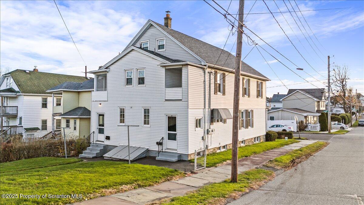 1446 Thackery Street Scranton, PA 18504 - Photo 4 of 25 a view of a white house with a yard and table and chairs under an umbrella