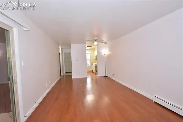 a view of an empty room with window and wooden floor