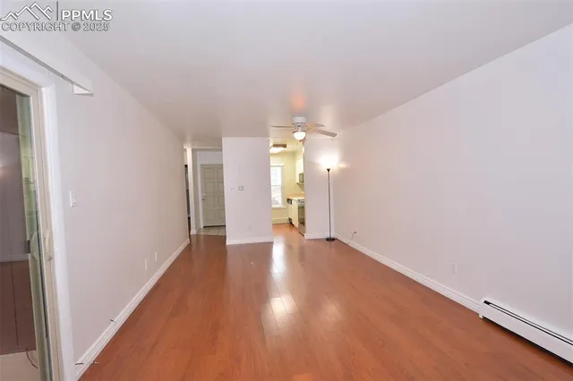 a view of an empty room with window and wooden floor