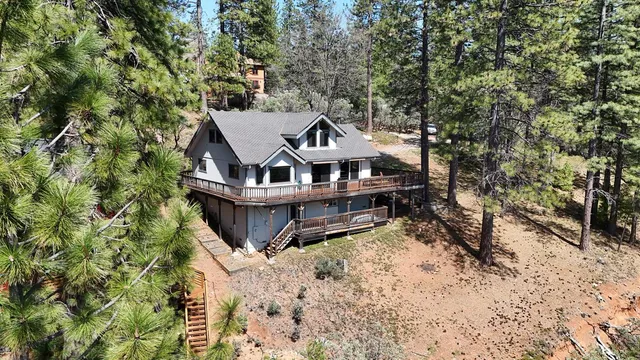 a view of a house with a large tree and wooden fence