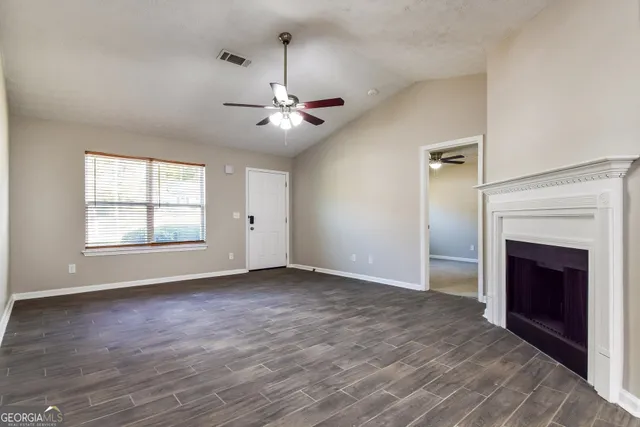an empty room with windows fireplace and a ceiling fan