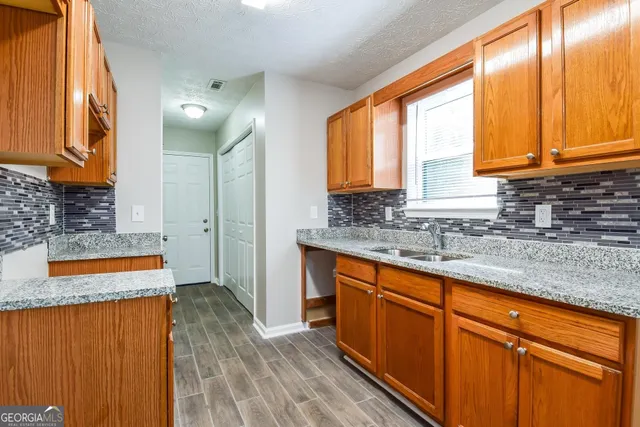 a kitchen with stainless steel appliances granite countertop wooden cabinets a sink and a large window
