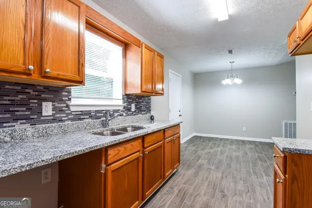 a kitchen with stainless steel appliances granite countertop wooden cabinets a sink and dishwasher with wooden floor