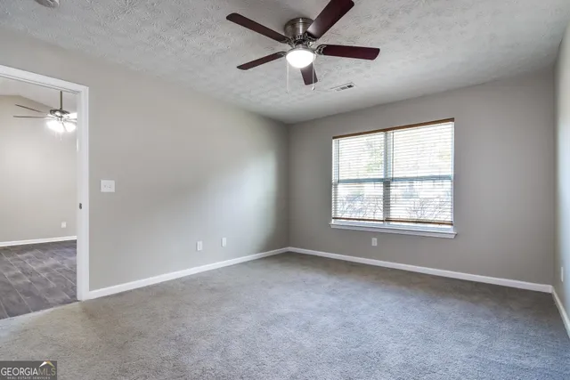 an empty room with ceiling fan and windows