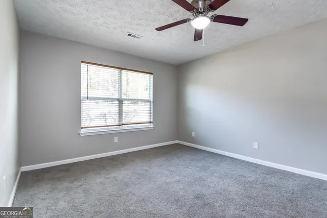 an empty room with a window and a fan