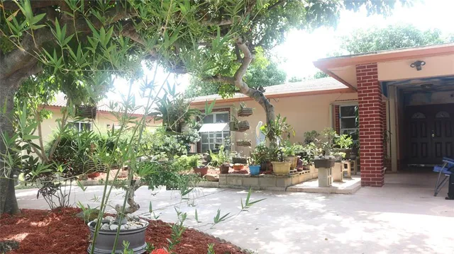 a view of a patio with table and chairs potted plants and large tree