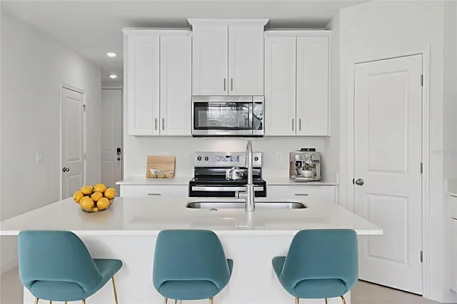 a kitchen with stainless steel appliances granite countertop a stove a refrigerator a dining table and chairs