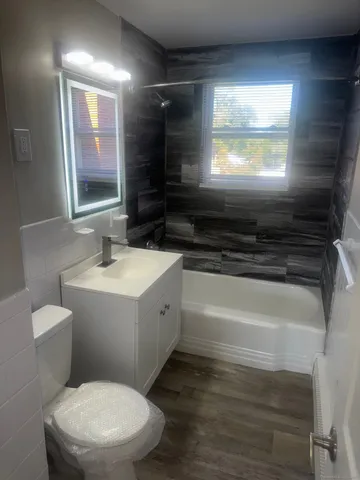 a bathroom with a sink a toilet a mirror a vanity and window
