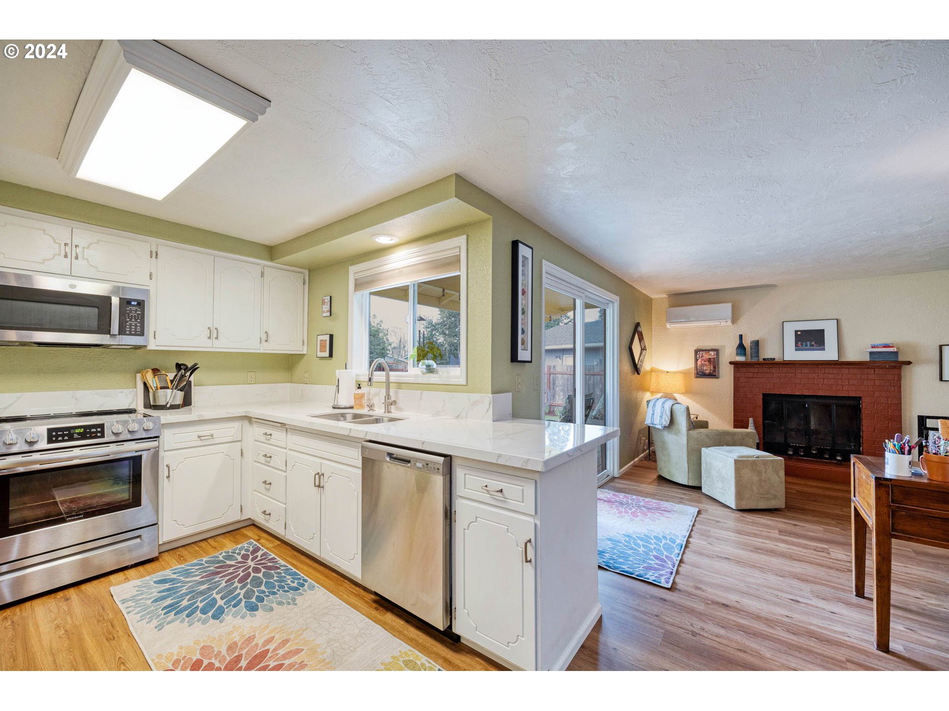 3672 Harlow Road Eugene, OR 97401 - Photo 12 of 36 a kitchen with stainless steel appliances granite countertop a stove top oven a sink dishwasher and white cabinets with wooden floor