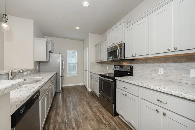 a kitchen with granite countertop white cabinets sink and stainless steel appliances