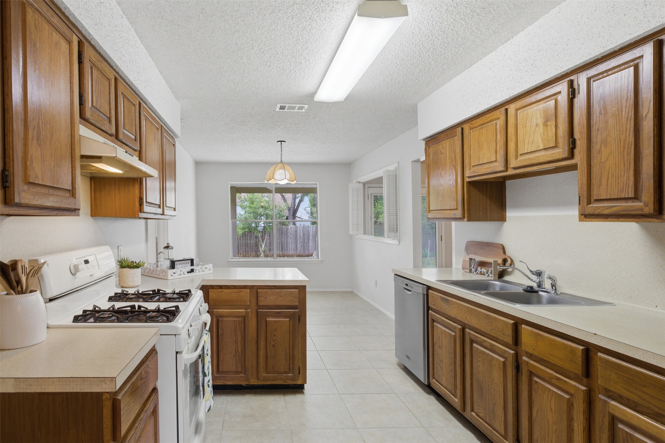 5305 Wolf Run Austin, TX 78749 - Photo 22 of 37 Kitchen featuring wood cabinetry, white countertops, a gas range, a double basin stainless steel sink, and tile flooring