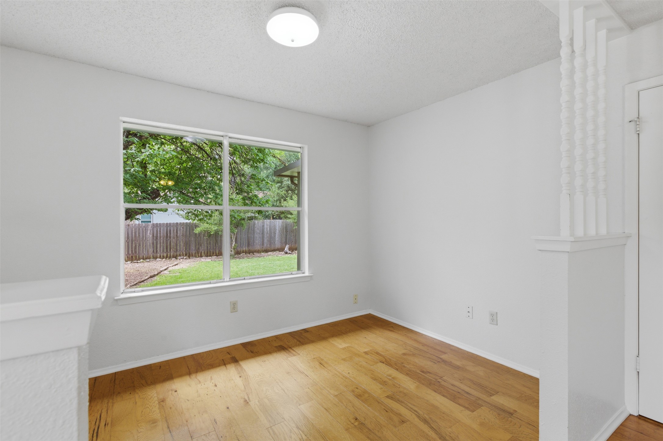 5305 Wolf Run Austin, TX 78749 - Photo 31 of 37 Bright interior space featuring a large window with outdoor views, light wood-finish flooring, white painted walls, and a decorative half-wall with balusters