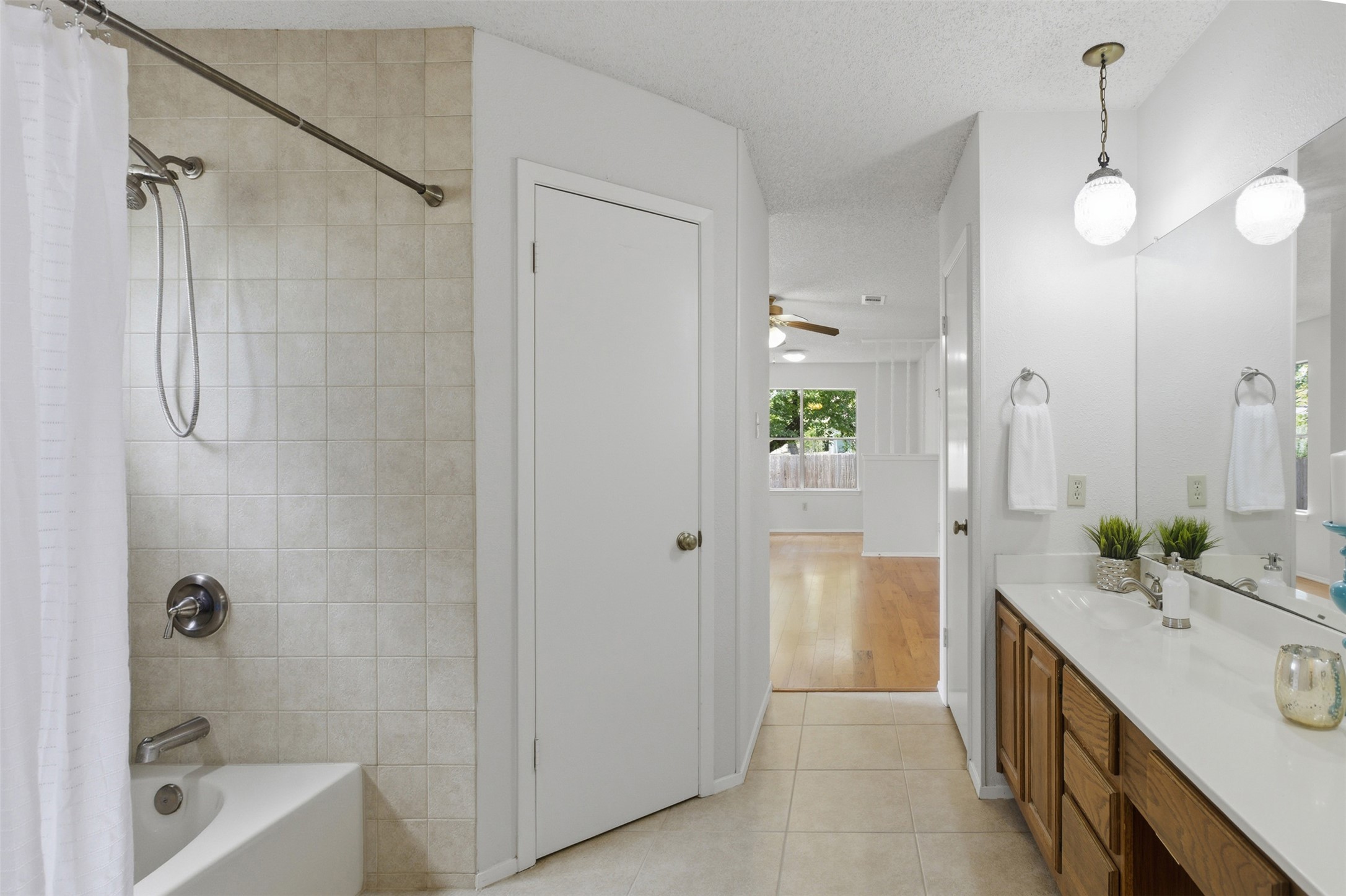 5305 Wolf Run Austin, TX 78749 - Photo 9 of 37 Bathroom featuring a tub/shower combination with tile surround, a vanity with a white countertop and wood-finish cabinetry, and tiled flooring