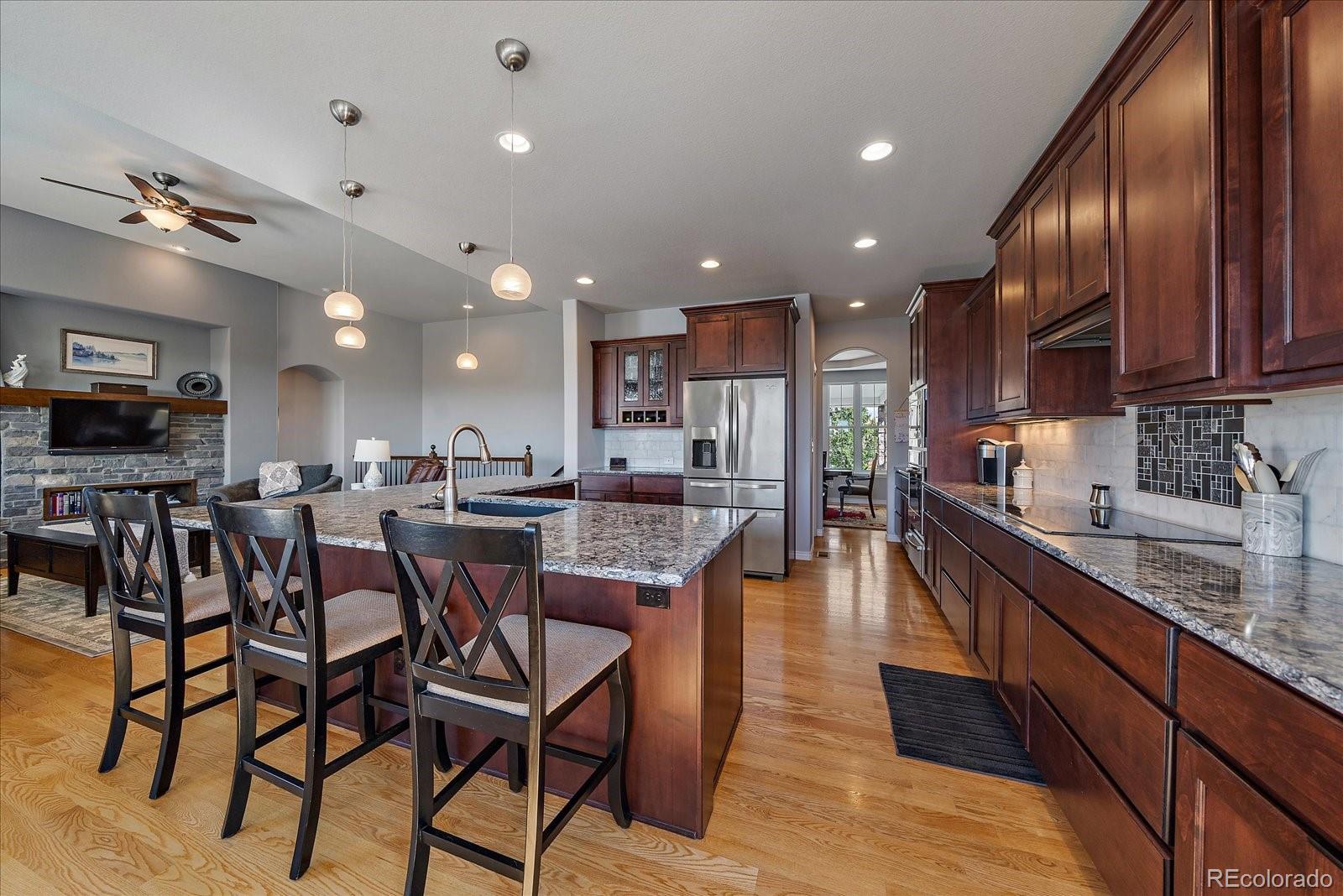 8412 Quaker Circle Arvada, CO 80007 - Photo 17 of 44 a kitchen with stainless steel appliances granite countertop a refrigerator a sink dishwasher a dining table and chairs with wooden floor