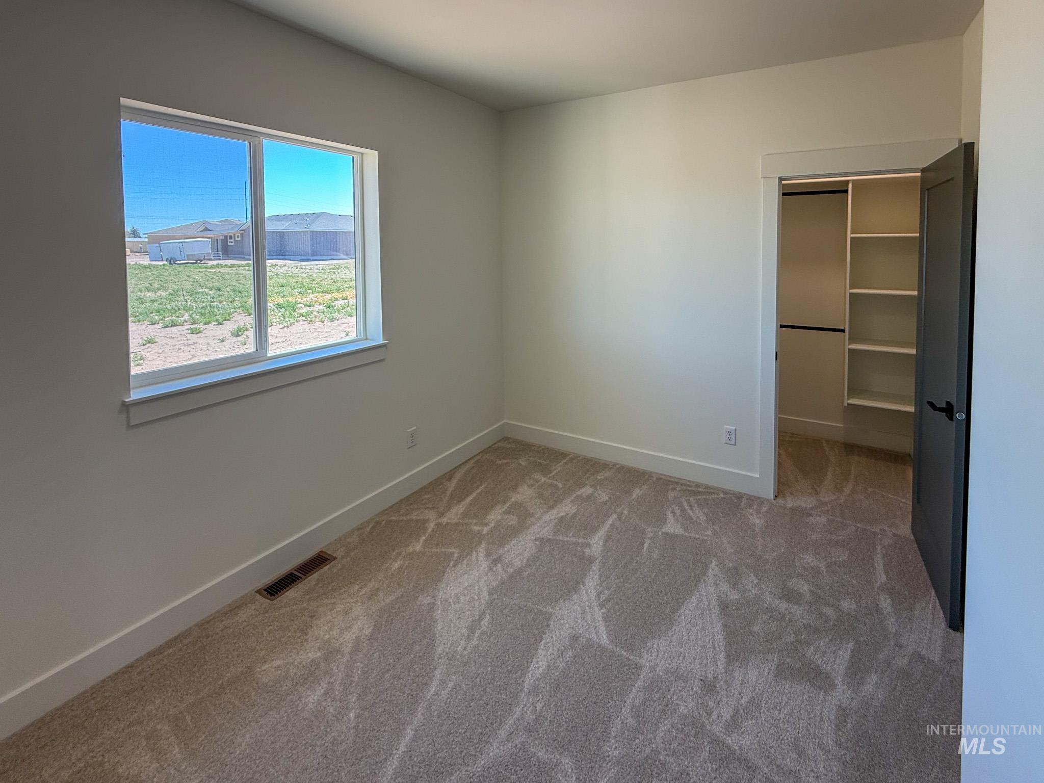 1108 Sage Rupert, ID 83350 - Photo 14 of 21 Carpeted room featuring a double-pane window, white trim, a dark gray interior door, and a closet with shelving and a hanging rod