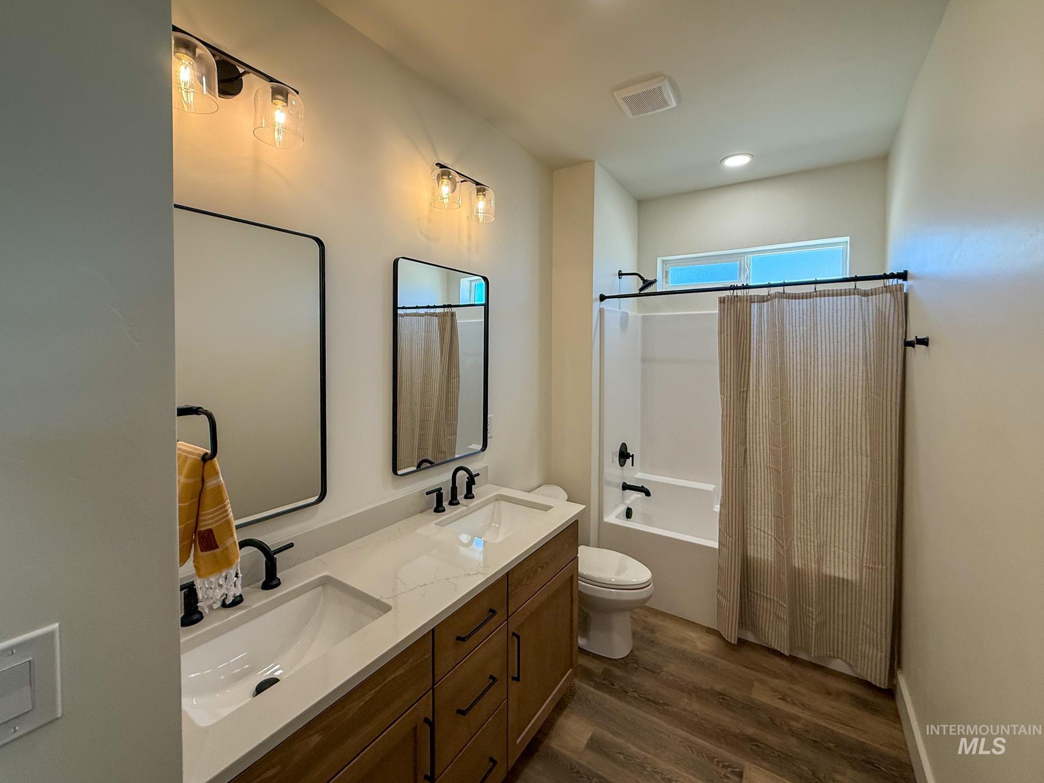 1108 Sage Rupert, ID 83350 - Photo 15 of 21 Bathroom featuring a dual vanity with a light-toned countertop, wood-finish cabinetry, and matte black fixtures