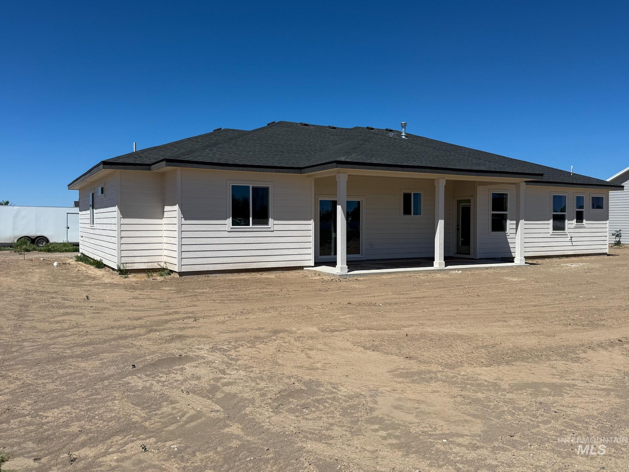 1108 Sage Rupert, ID 83350 - Photo 21 of 21 Rear exterior featuring white horizontal siding, a covered patio with white columns, a dark shingle roof, and multiple windows