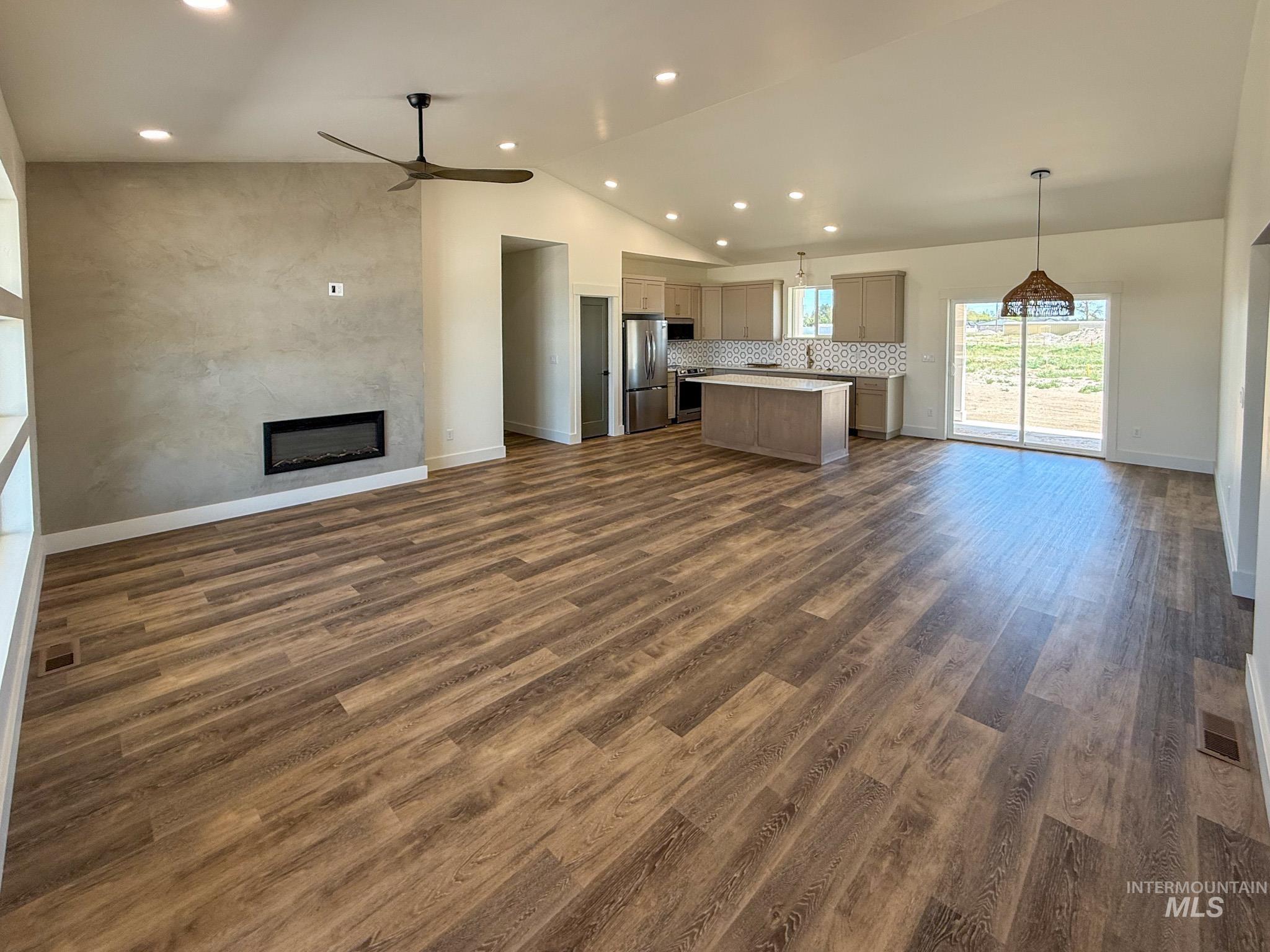 1108 Sage Rupert, ID 83350 - Photo 8 of 21 Spacious living area featuring wood-finish flooring, a contemporary fireplace with a textured accent wall, and a vaulted ceiling with recessed lighting