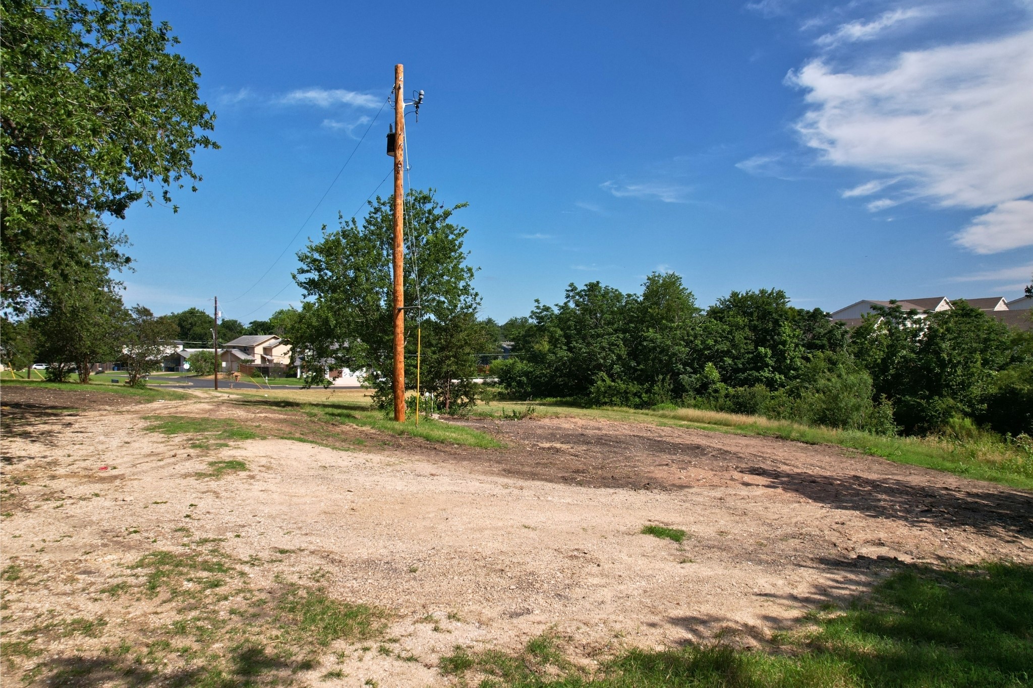 2610-2606 Metcalfe Road Austin, TX 78741 - Photo 6 of 20 A spacious lot offering potential for development amidst a backdrop of lush trees and blue skies.