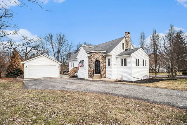 a view of a white house with a yard and large trees