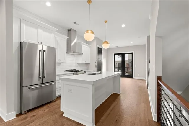 a kitchen with stainless steel appliances granite countertop a refrigerator a oven a stove and a sink with wooden floor