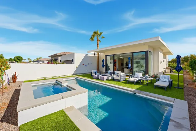 a view of a backyard with swimming pool and couches chairs