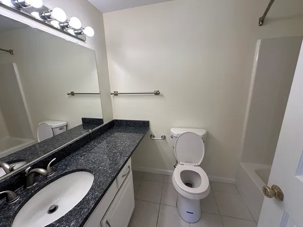 a bathroom with a granite countertop sink a toilet and mirror