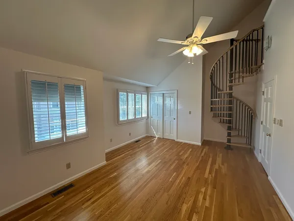 a view of empty room with wooden floor and fan