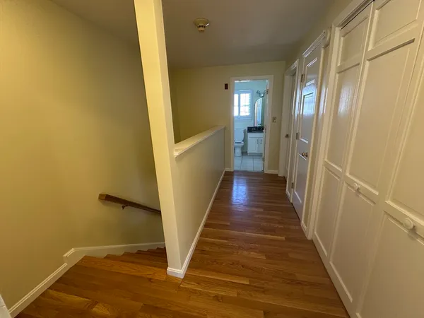 a view of a hallway with wooden floor and staircase