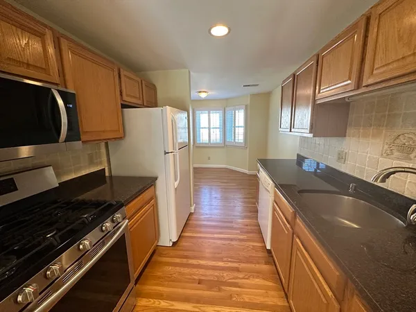 a kitchen with granite countertop stainless steel appliances a sink stove top oven and cabinets