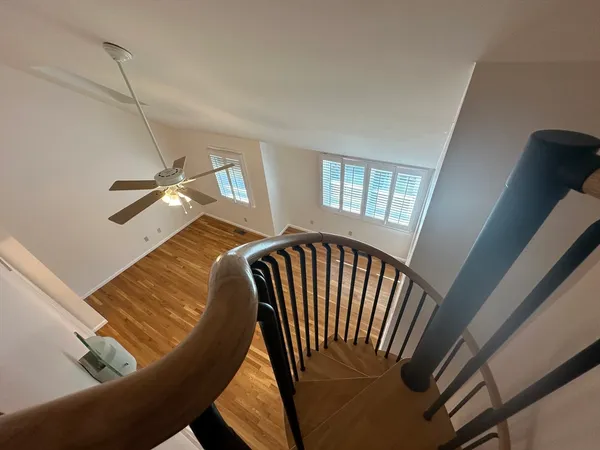 a view of staircase with wooden floor and fan
